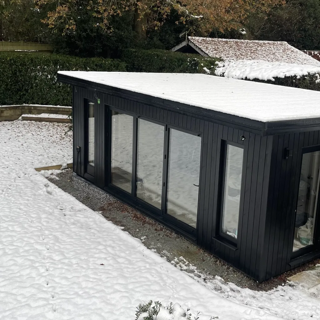 Exterior view of a garden room covered in snow