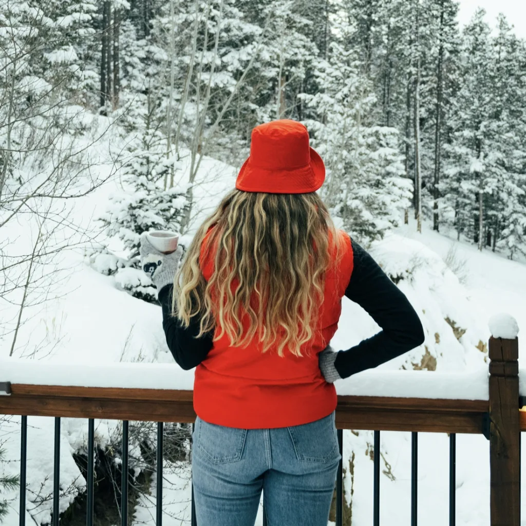 Woman standing on her garden room decking, observing the snow